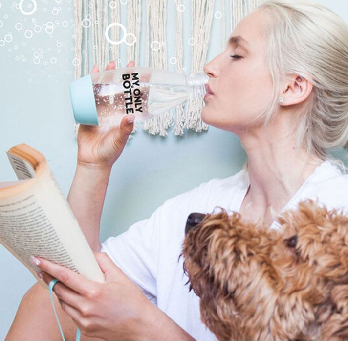 žena se psem která pije z opakovatelně použitelné lahve