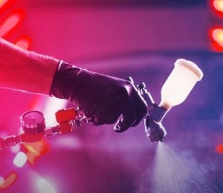 ruka v rukavice stříkající lak na automobil