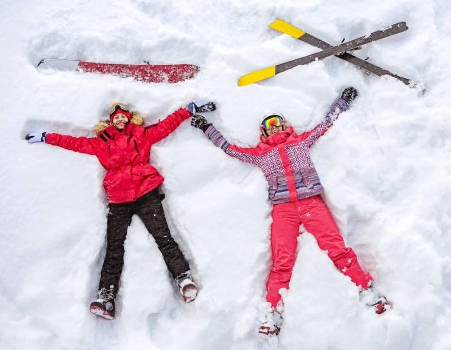 dvě ženy ve sněhu v lyžařském oblečení a lyže ve sněhu