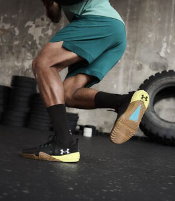 Cvičící muž v zelených šortkách a černých fitness teniskách