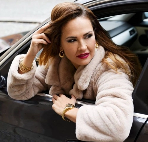 žena vyklánějící se z auta se zlatými náušnicemi a náramky