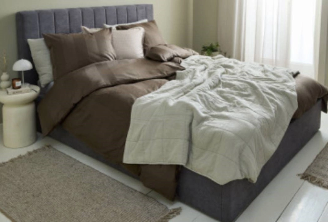 ložnice s ustlánou postelí, nočním stolkem a koberečkem