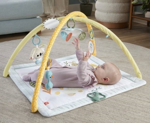 dítě ležící v obýváku na podložce s hračkami