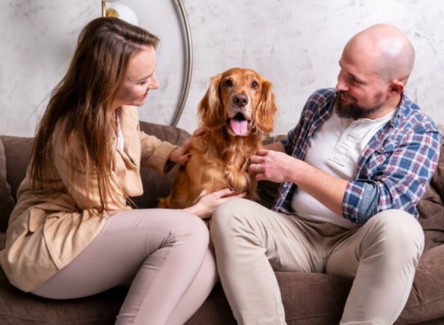 žena a muž sedící na sedačce a mezi nimi pes