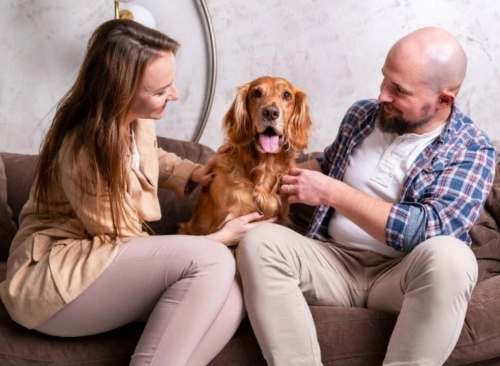 žena a muž sedící na sedačce a mezi nimi pes