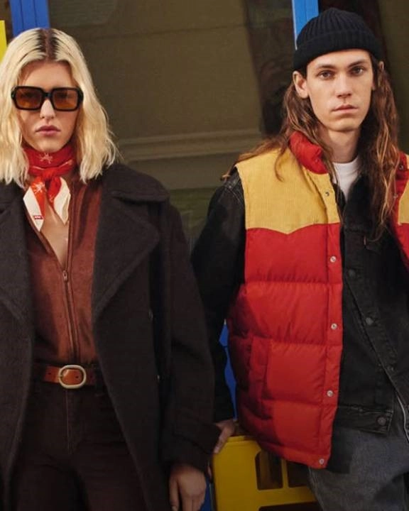 žena s brýlemi, v černém kabátě a hnědé blázce a muž s čepicí a v barevné bundě