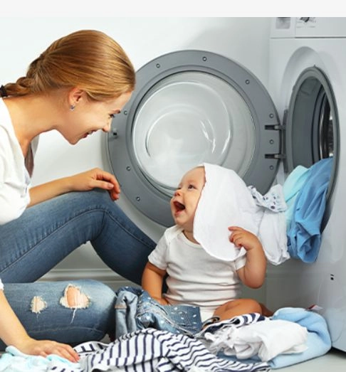 žena s dítětem u prádla při pračce