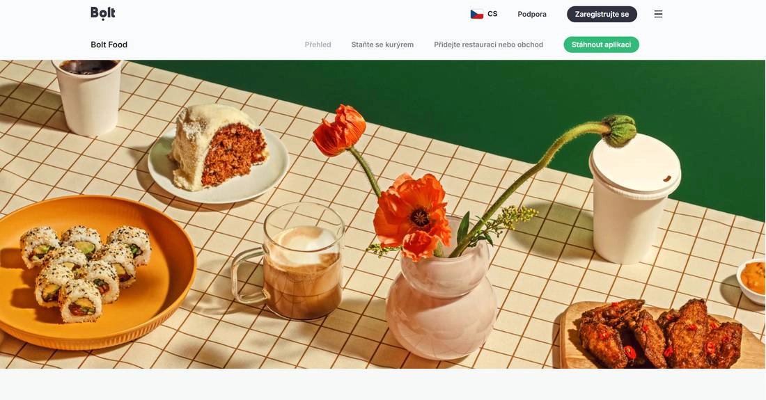Stránka Bolt Food s prostřeným stolem s jídlem a pitím i květinou ve váze