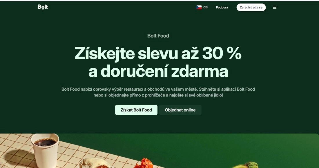 Stránka Boltu v zelené s popisem a kouskem prostřeného stolu s kelímkem pití