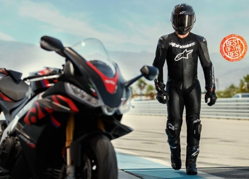 motorkář v motoristickém oblečení is přilbou a vedle něj motorka