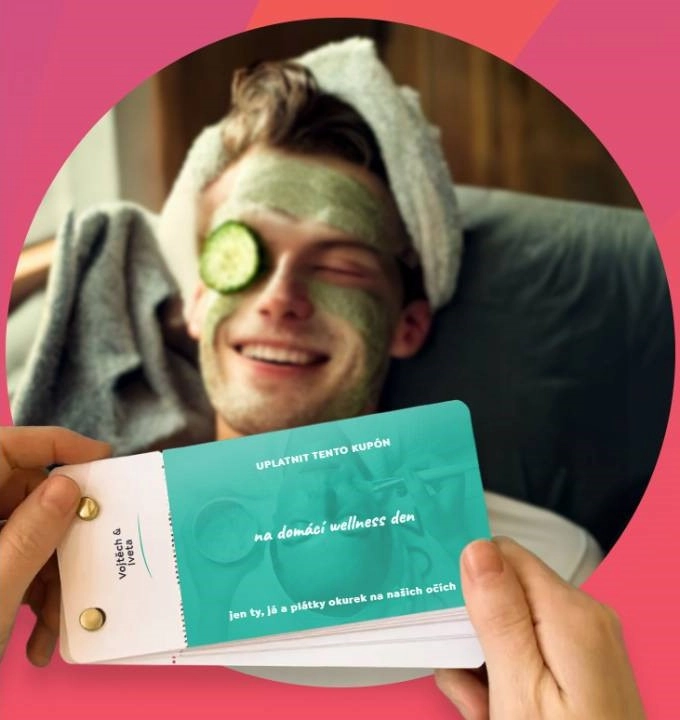 dárkový kupón v rukou a muž s pleťovou maskou, ručníkem na hlavě a okurkou na oku v křesle