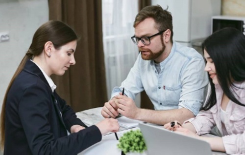 dvojice sedící s bankéřkou nad možnostmi půjčky