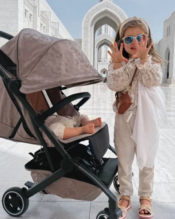 holčička v módním oblečení a dětský kočárek s panenkou