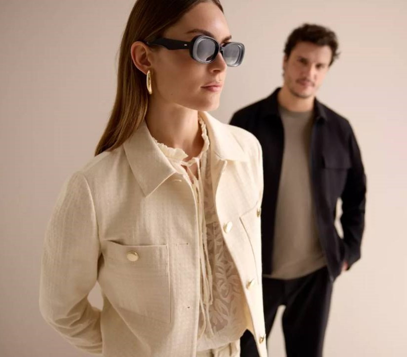 žena v tričku, bundě a s černými brýlemi a muž v tmavém tričku, bundě a kalhotách