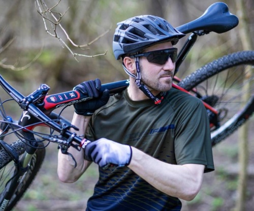 cyklista s kolem na rameni v přírodě