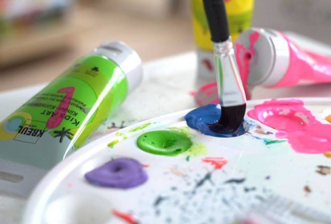 kreativní svět - paleta s barvami a štětcem a vedle ní tuby s barvami