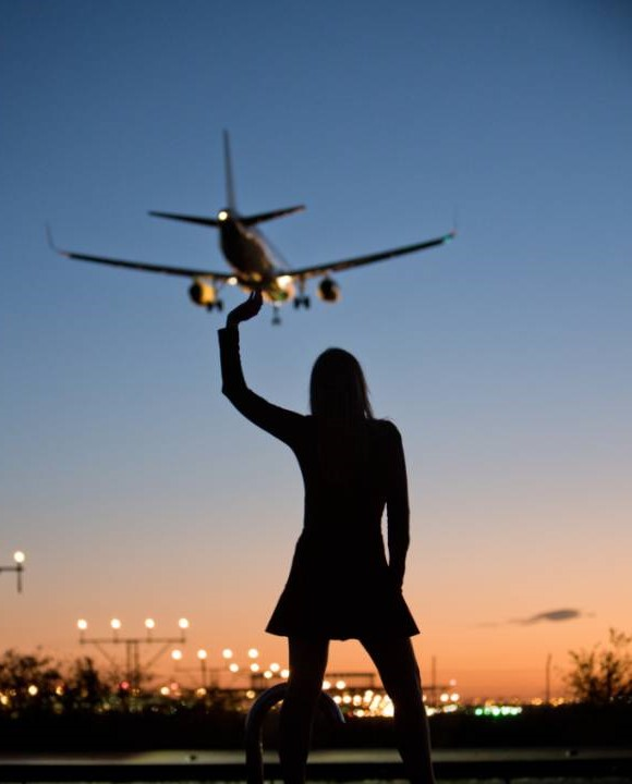 Vueling - letadlo ve vzduchu a silueta ženy, která mu kývá
