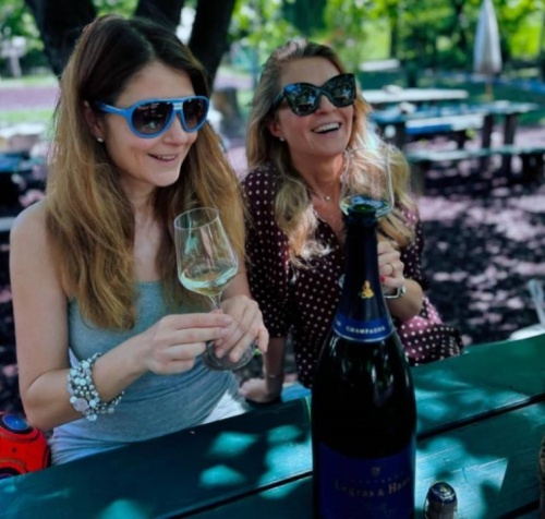 8Wines - dvě vysmáté ženy sedící na terase se sklenkou bílého vína a lahví vína na stole