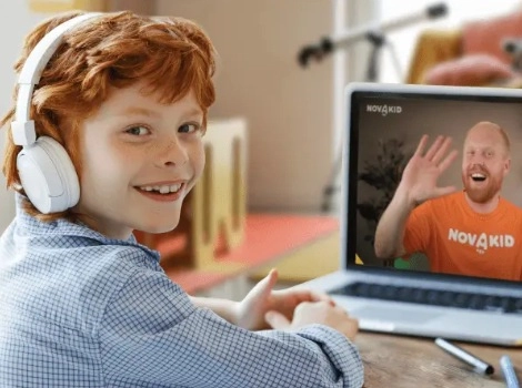 Díky se sluchátky sedí za laptopem a usmívá se