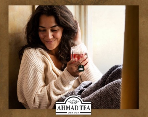 Ahmad Tea - žena ve svetru pod dekou pijící horký čaj