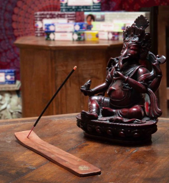 indická soška a doutnající vonná tyčinka na stolku